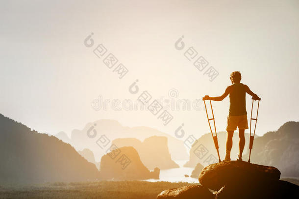 残疾人<strong>拄着拐杖</strong>站在大石头上，就像胜利者