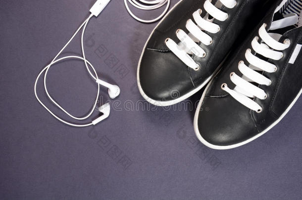 黑色运动鞋与白色鞋带和耳机在黑暗的背景