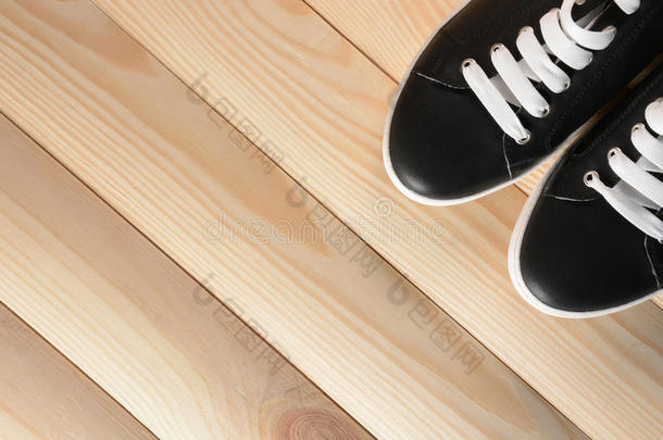 黑色运动鞋，白色鞋带在木制背景上