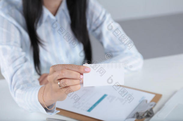女商人拿着空白的参观卡，坐在桌子上
