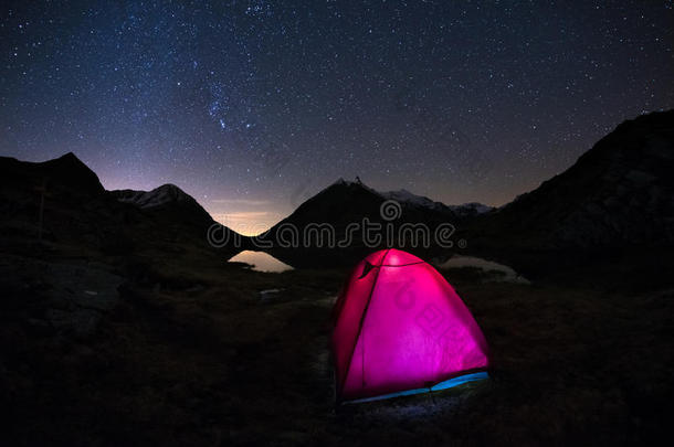 在星空下<strong>露营</strong>，在意大利法国阿尔卑斯山的高空上在银河弧下<strong>露营</strong>。 前景中发光的<strong>帐篷</strong>。 冒险