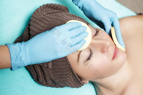 医生美容师用海绵清洁皮肤女人。 美容治疗护肤品面部。 水疗程序
