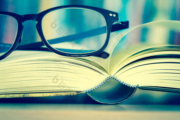 关闭打开的书页和阅读眼镜与模糊的