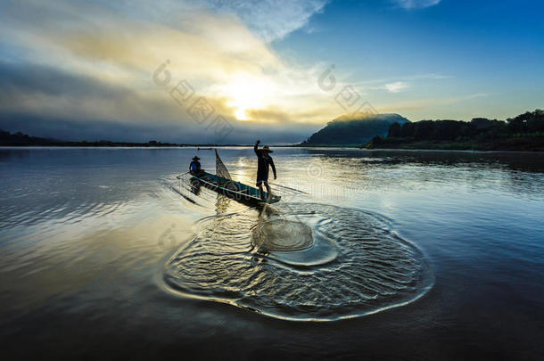 亚洲渔民在木船上撒网在日出前的清晨在自然