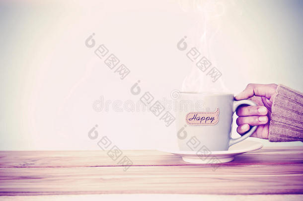 手拿一个咖啡杯杯子，在木<strong>桌</strong>上贴上快乐的单词标<strong>签</strong>，浪漫和爱情背景。 快乐和放松的概念，