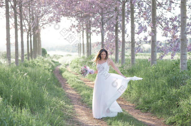 美丽时尚的新娘穿着婚纱在春天的森林里跳舞。