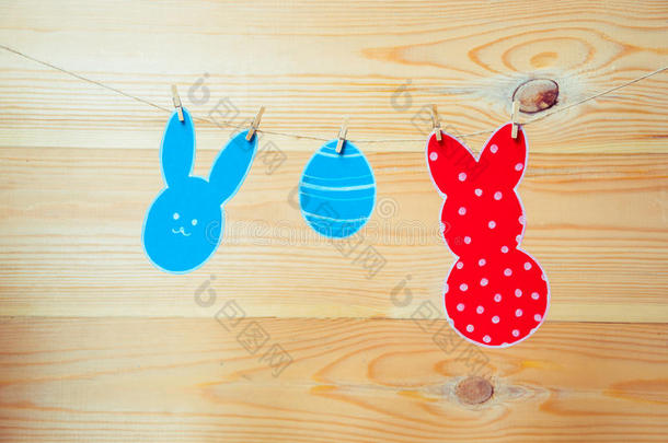 彩色纸兔和纸蛋剪影框架的特写悬挂在木制背景的绳索上