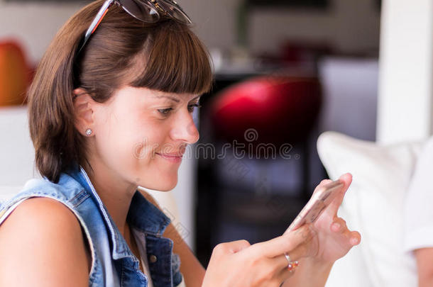 美丽的年轻女子在咖啡馆使用一个应用程序发送短信在她的智能手机设备。 巴厘岛。