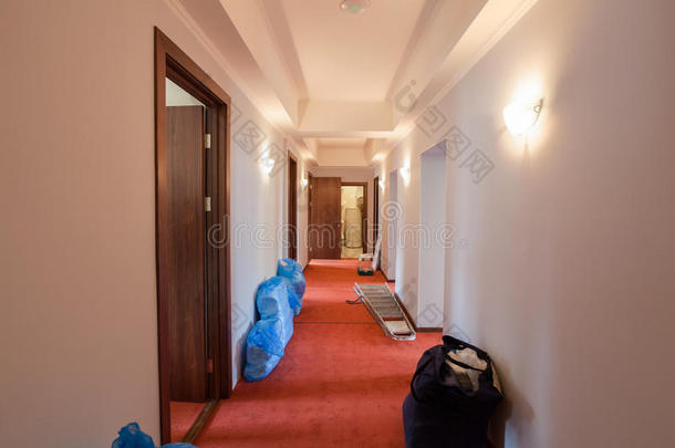 在酒店的走廊地板上，有床、亚麻布和梯子的袋子正在翻新和施工中。