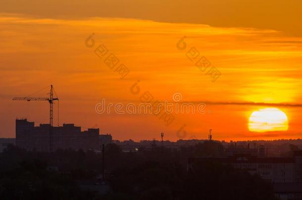 日出越过城市地平线-红色的太阳,建筑物吊车,剪影