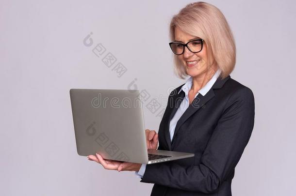 微笑的中部老年的女人和便携式电脑