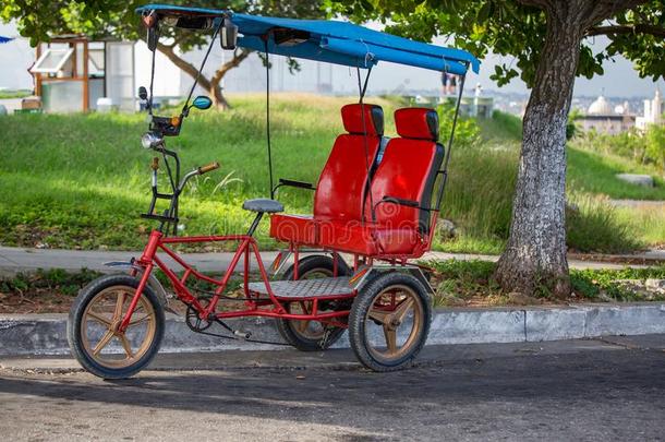 红色的自行车出租车为两个乘客采用哈瓦那雪茄,古巴