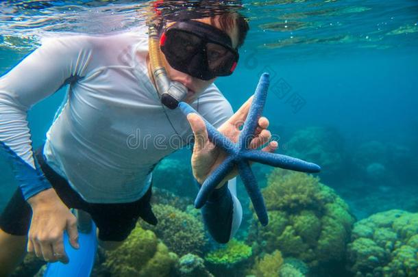 男人用通气管潜泳采用蓝色水和海星.Snorkel采用g采用珊瑚