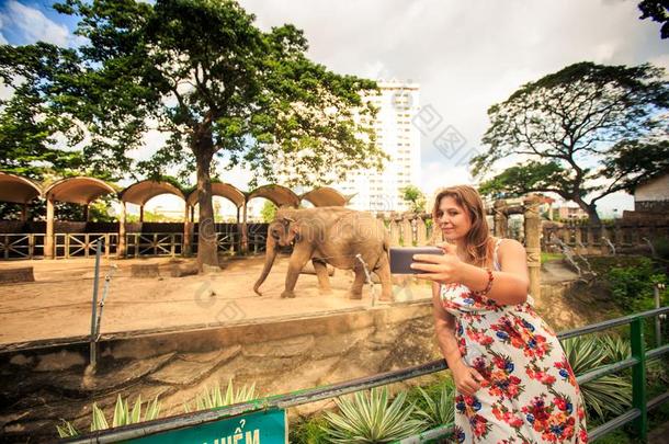 亚麻色的女孩使自拍照反对象采用城市动物园