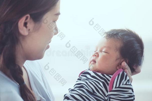 漂亮的亚洲人新生的婴儿女孩睡眠向母亲`英文字母表的第19个字母手.