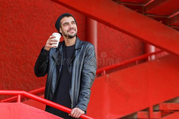 英俊的年幼的男人喝饮料咖啡豆在户外.