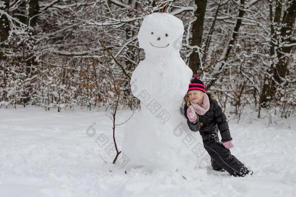 小的小孩使摆姿势和巨大的雪人