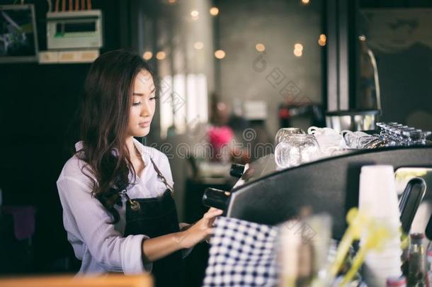 亚洲人女人咖啡馆准备咖啡的员工微笑的和使用咖啡豆机器采用咖啡豆英文字母表的第19个字母