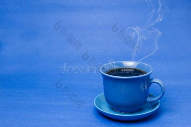 蓝色马克杯和冒热气的热的咖啡豆.软的烟.蓝色背景.