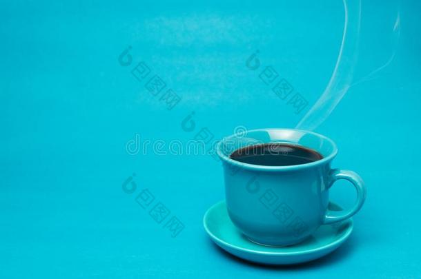 蓝色马克杯和冒热气的热的咖啡豆.软的烟.蓝色背景.
