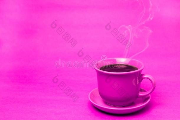 粉红色的马克杯和冒热气的热的咖啡豆.软的烟.粉红色的背景.