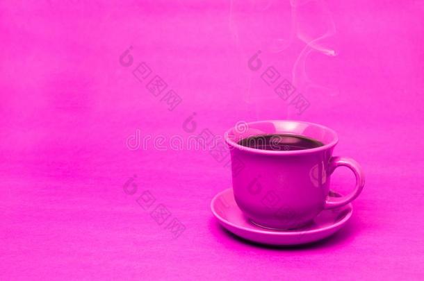 粉红色的马克杯和冒热气的热的咖啡豆.软的烟.粉红色的背景.