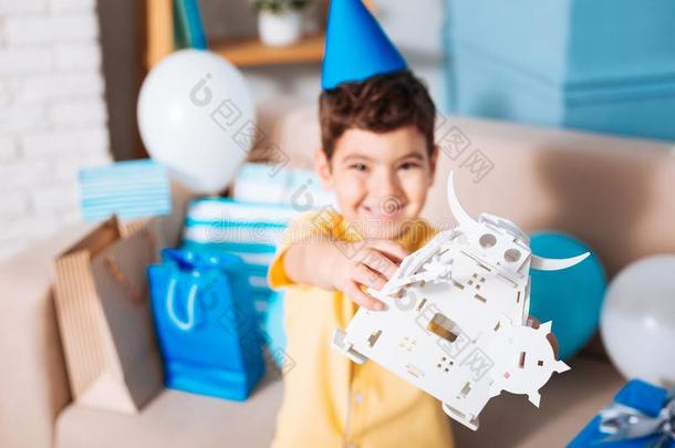微笑的生日男孩展映他的白色的玩具机器人