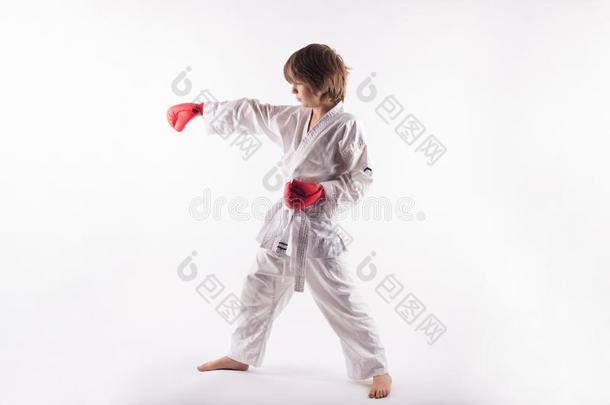 空手道小孩使人疲乏的和服和红色的拳击拳击手套做练习