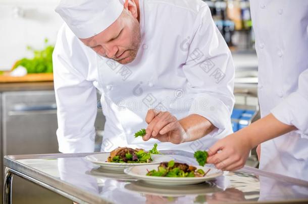 两个专注的厨师长准备牛排盘在美食家饭店