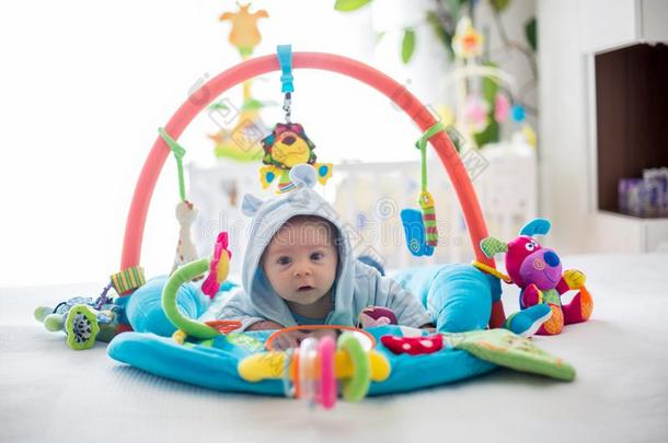 漂亮的婴儿男孩向富有色彩的健身房,演奏和绞死玩具在家