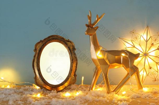 金发光的驯鹿和空的照片框架向下雪的木制的表