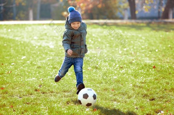 漂亮的小的男孩演奏足球向场地