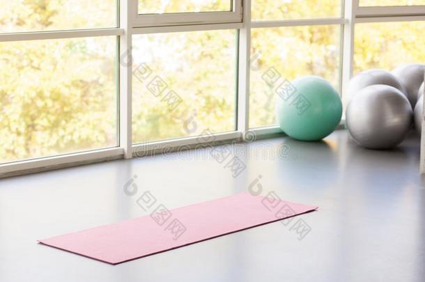 <strong>瑜伽</strong>席子躺向灰色地面在近处窗和<strong>健身球</strong>