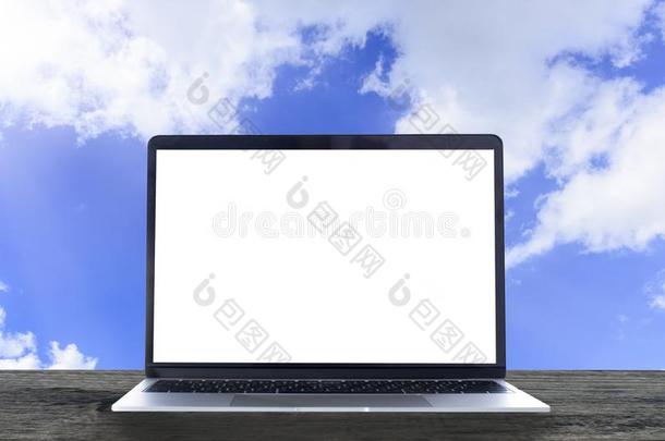 便携式电脑和白色的空白的屏幕向木制的表和蓝色天背