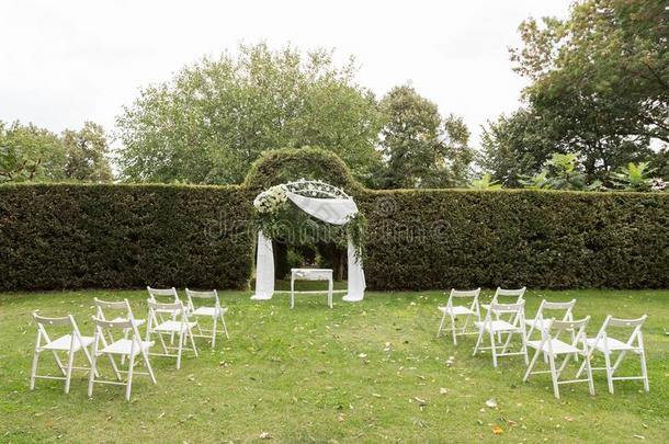 婚礼典礼放置在上面.婚礼弓形和白色的椅子向绿色的