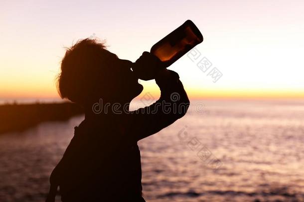轮廓关于年幼的男人喝饮料葡萄酒从瓶子