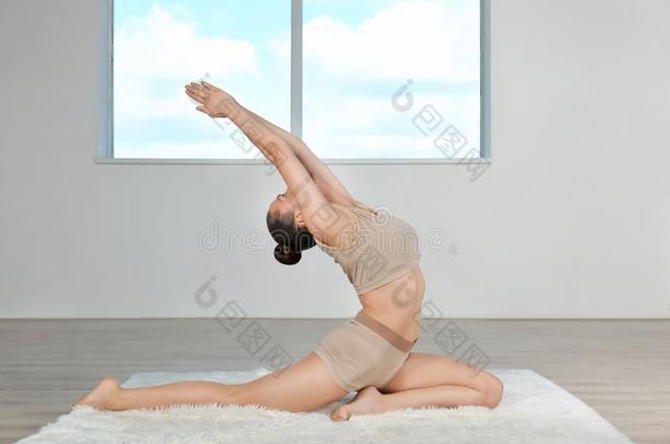 年幼的美丽的女人做瑜伽使摆姿势采用房间