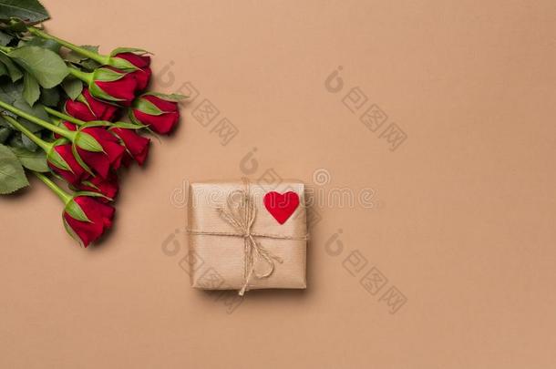 红色的玫瑰和赠品和心符号向米黄色背景.