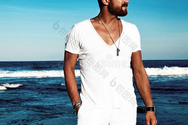 时尚男人模型使人疲乏的白色的衣服使摆姿势向蓝色海后面