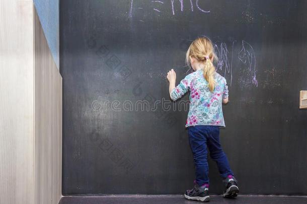 漂亮的小的女孩文字向黑板