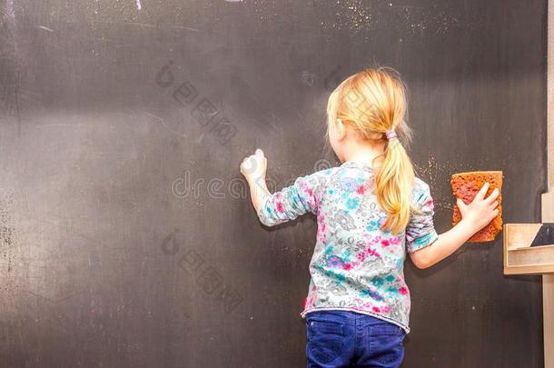 漂亮的小的女孩文字向空的黑板
