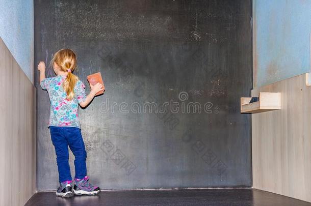 漂亮的小的女孩文字向空的黑板
