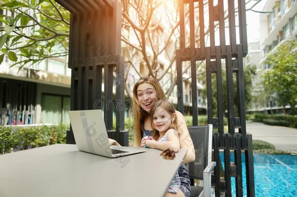 母亲和女儿使用便携式电脑为在线的购物向背景