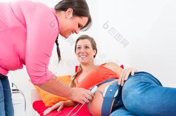 微笑的期待的母亲和接生婆调节分娩监护仪