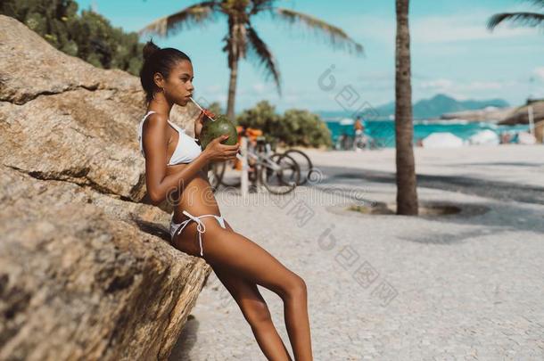 非洲式发型女孩喝饮料<strong>椰子树</strong>水从<strong>椰子树</strong>nut在近处海滩