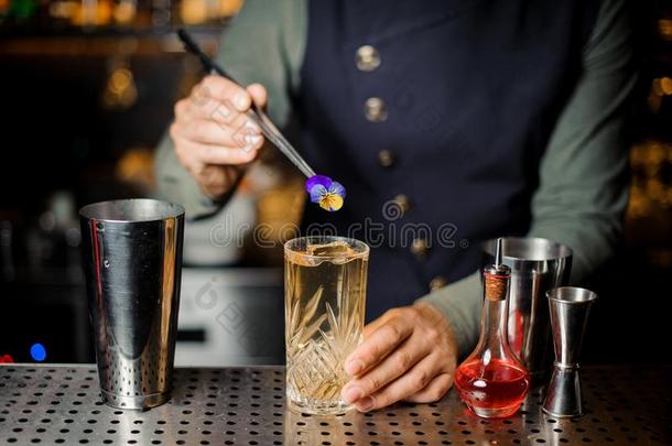 酒吧间销售酒精饮料的人最后的准备的鸡尾酒和一紫罗兰花