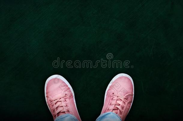 女孩使人疲乏的粉红色的帆布鞋子向黑板和复制品空间