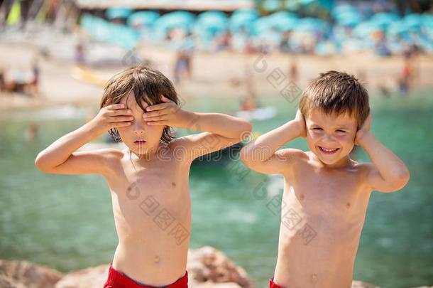 两个孩子们向指已提到的人海滩,男孩,演奏和制造有趣的面容