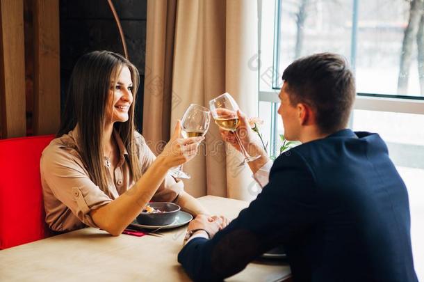 年幼的幸福的对浪漫的日期喝玻璃关于白色的葡萄酒在关于