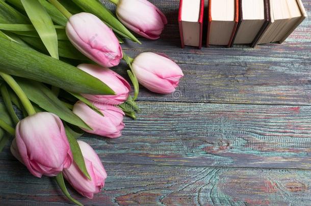 粉红色的郁金香和书向木制的背景